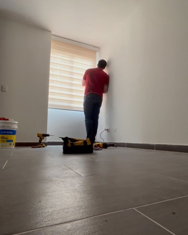 Instalador montando una persiana sheer en un apartamento vacío