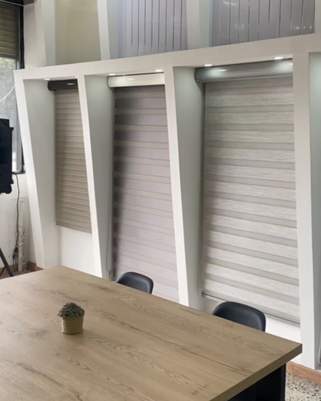 Sala de exhibición con persianas y mesa de madera