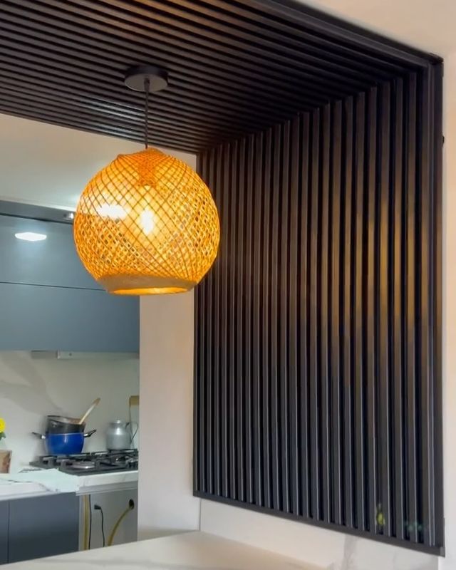 Pared de cocina revestida con listones de WPC negro y lámpara colgante